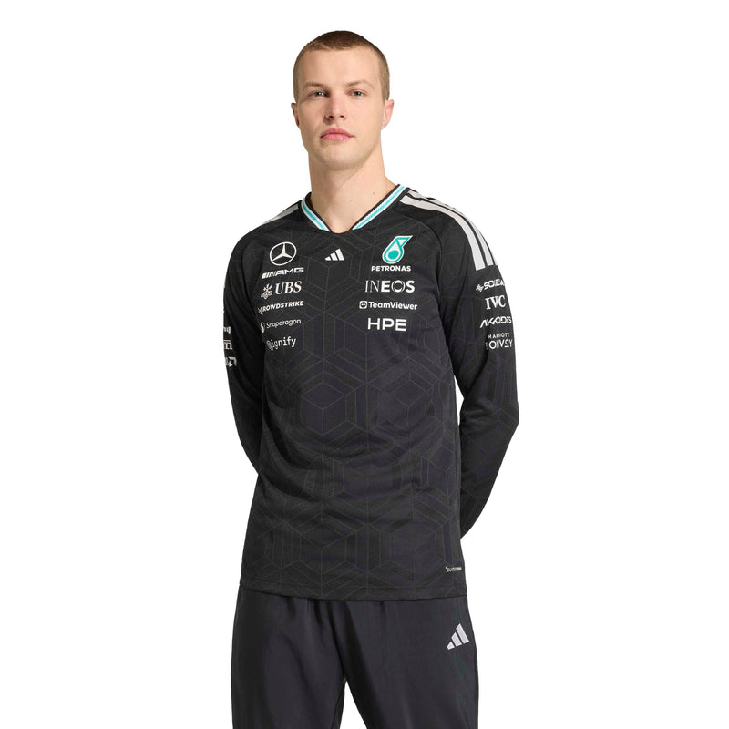 adidas male model wearing a black Mercedes Petromas long-sleeve sports jersey with white and light blue accents, featuring sponsor logos and the Adidas logo, against a plain white background.